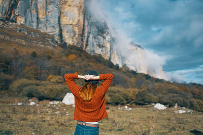 Rear view of man standing on mountain against sky