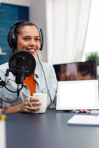 Portrait of young woman using mobile phone at desk in office