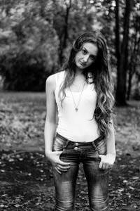 Portrait of young woman standing against trees