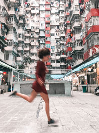 Full length of man walking on street against buildings in city