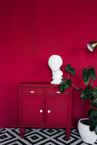 Stylish interior of the room with scarlet walls, a red chest of drawers, a female head sculpture