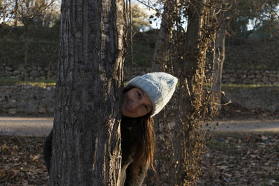 Smiling woman behind trunk of tree