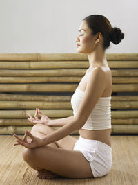 Woman with cross-legged meditating indoors