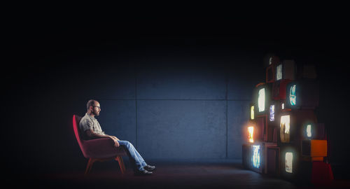 Young woman sitting on chair against wall