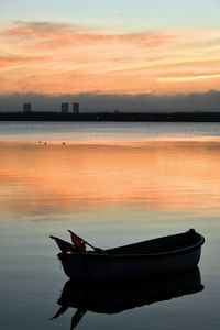 Boat moored on sea against sky during sunset