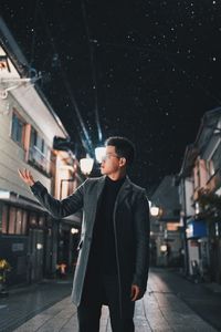 Young man standing in city at night