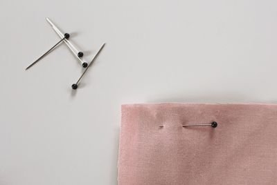 Directly above view of thumbtacks with textile on white background