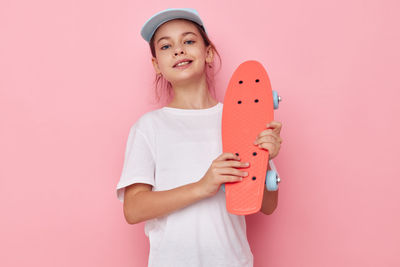 Portrait of young woman holding book against pink background