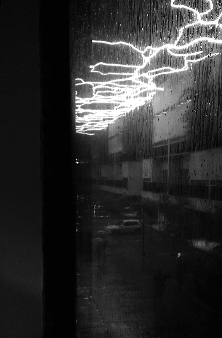ILLUMINATED BUILDINGS SEEN THROUGH GLASS WINDOW