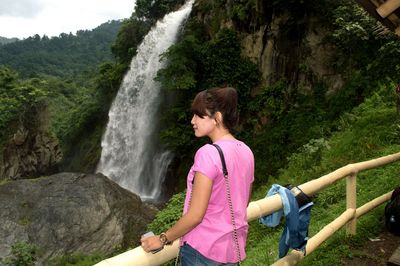 Woman standing against waterfall