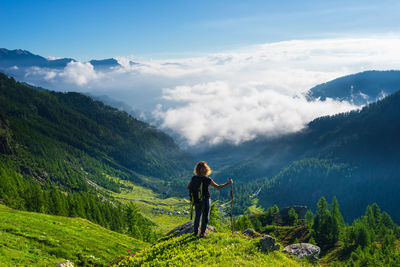 Rear view of man standing on mountain against sky