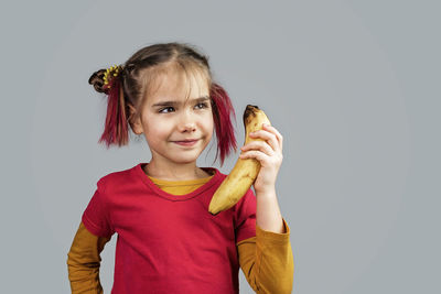 Portrait of smiling girl standing against gray background