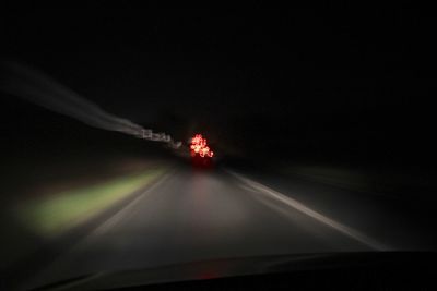 Illuminated car on road against sky at night