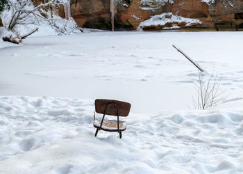 Landscape with a simple wooden chair on the river bank opposite a beautiful sandstone cliff