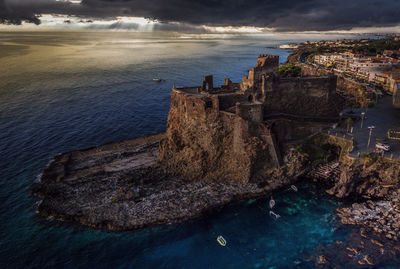 High angle view of abandoned castle by sea against storm clouds