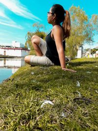 Side view of woman sitting on grassy field at public park