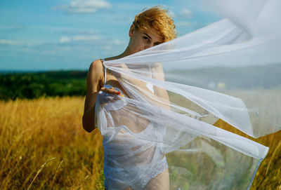 Blonde girl in white lingerie in summer field