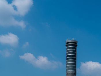 A tall building in blue sky fluffy cloud summer weather background with copy space 