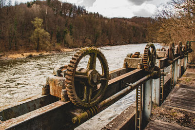 Rusty metal railing by river against sky