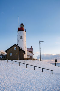 Lighthouse on snow covered building against sky