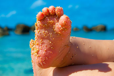 Low section of baby covered with sand at beach