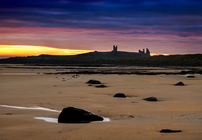 View of lighthouse on beach during sunset