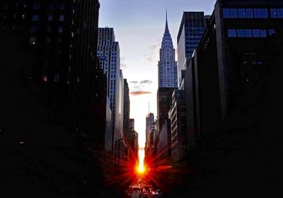 Digital composite image of buildings against sky during sunset