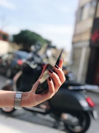 Close-up of hand using mobile phone on road