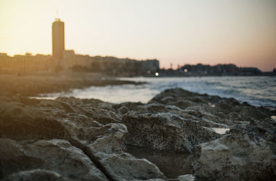 Rocks on beach against sky during sunset