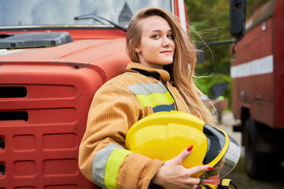 Portrait of female firefighter standing by truck