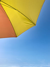 Low angle view of colorful umbrella against clear blue sky