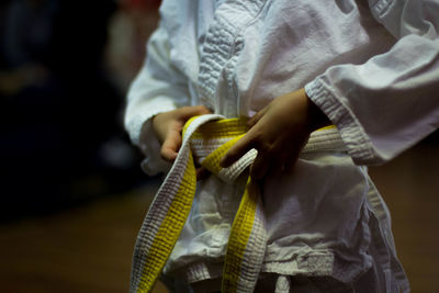 Midsection view of person tying karate belt