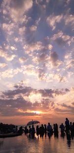 People on beach against sky during sunset