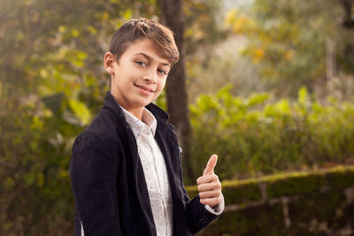 Portrait of teenage boy gesturing thumbs up in yard
