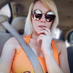 Young woman wearing sunglasses sitting in car