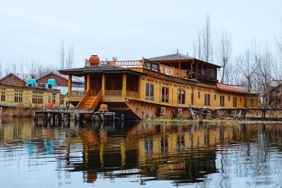 Reflection of building in river against sky during winter