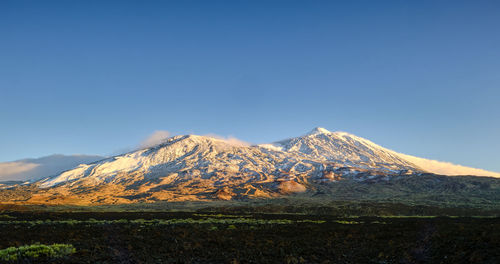 Scenic view of snowcapped mountains against blue sky