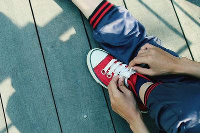 Low section of person tying shoelace on floorboard