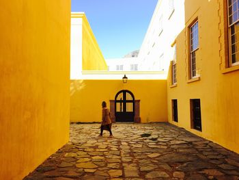 Full length of boy walking on yellow umbrella against sky