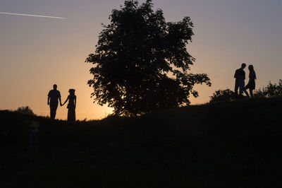 Silhouette couple by tree against sky during sunset