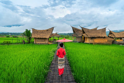 Rear view of woman standing on field against sky