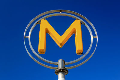 Low angle view of letter m symbol against clear blue sky