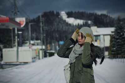 Woman in warm clothes standing on snow covered street