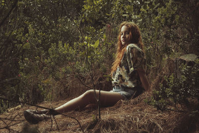 Portrait of woman sitting on field against plants