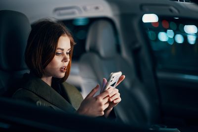 Young woman using mobile phone while sitting in car