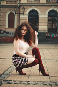 Portrait of beautiful young woman against building