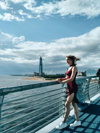 Full length of young woman standing on river against sky