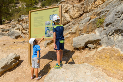 Side view of two people standing on rock