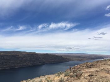 Rear view of woman standing on cliff by columbia river against sky