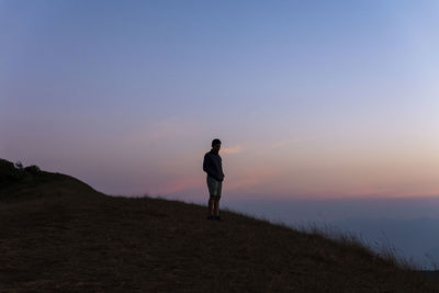 Full length of man standing on land against sky during sunset